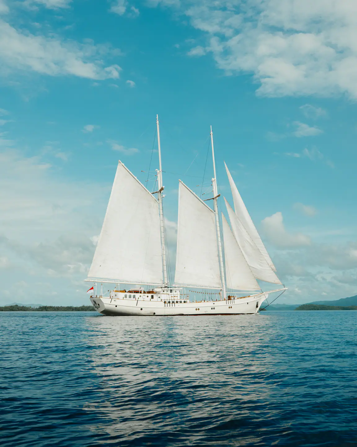 Mutiara Laut schooner yacht sailing across calm Indonesian waters.