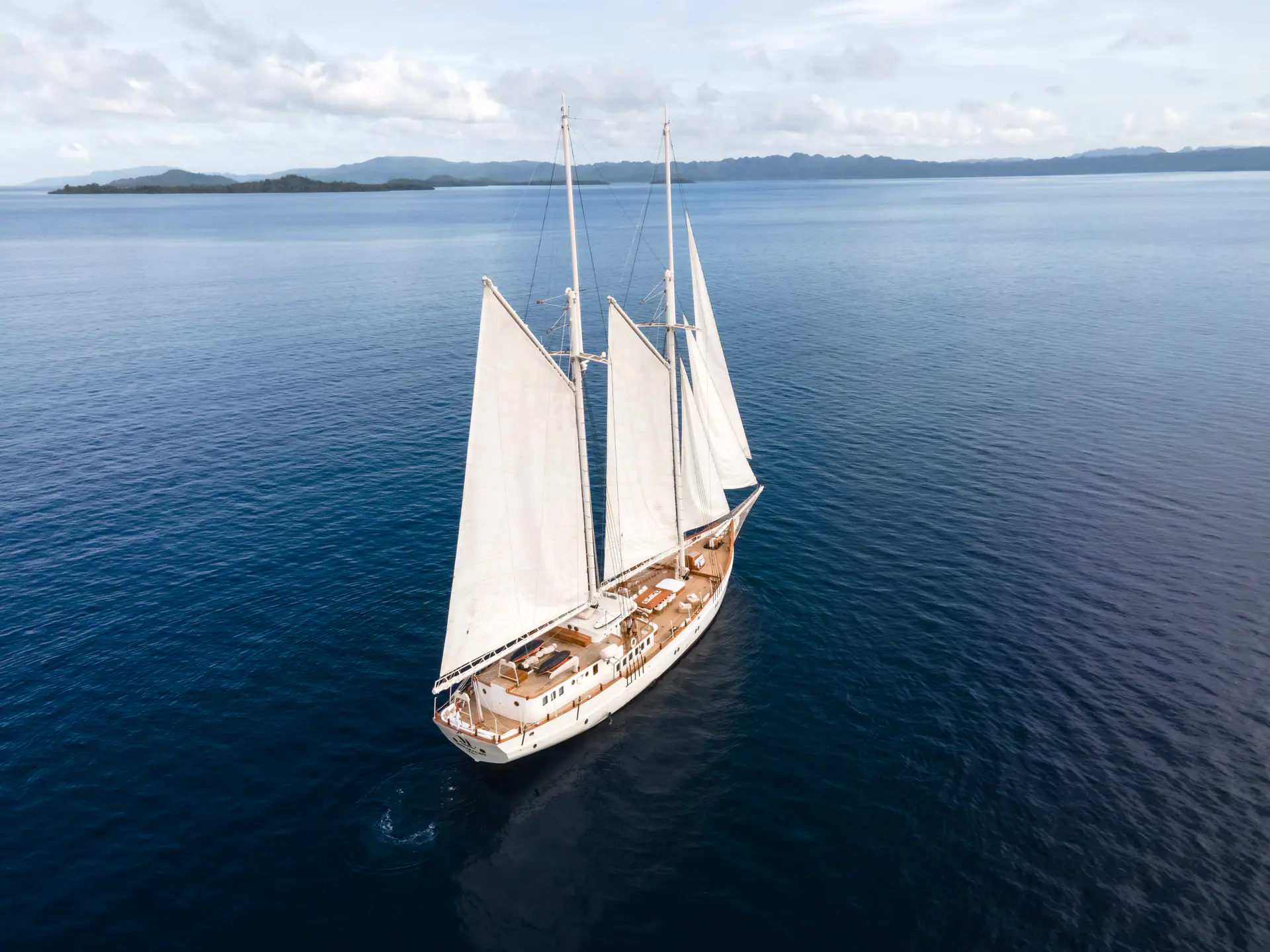 Mutiara Laut aerial view of the yacht sailing across deep blue ocean.