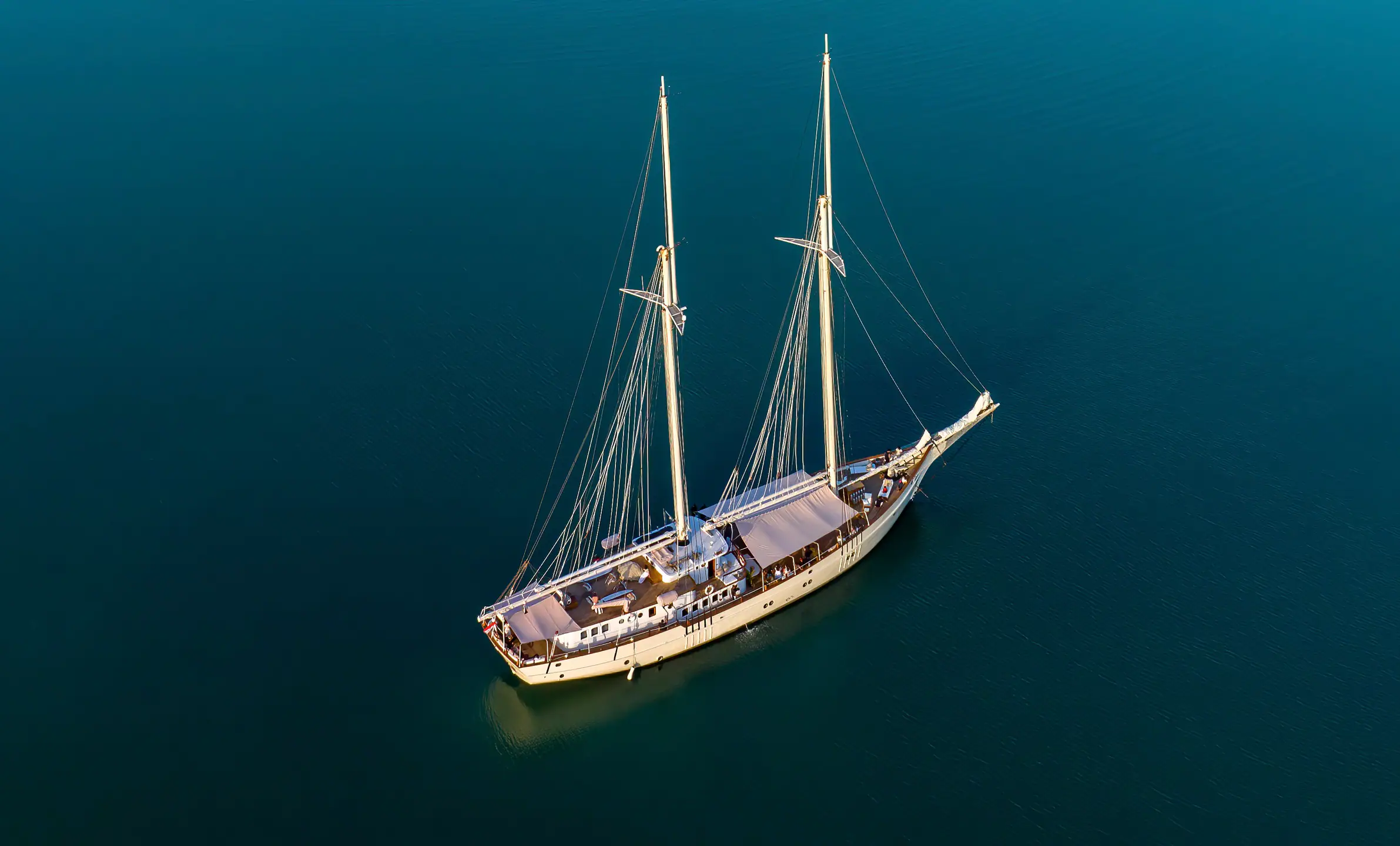 Mutiara Laut aerial view of the yacht anchored in deep turquoise waters.
