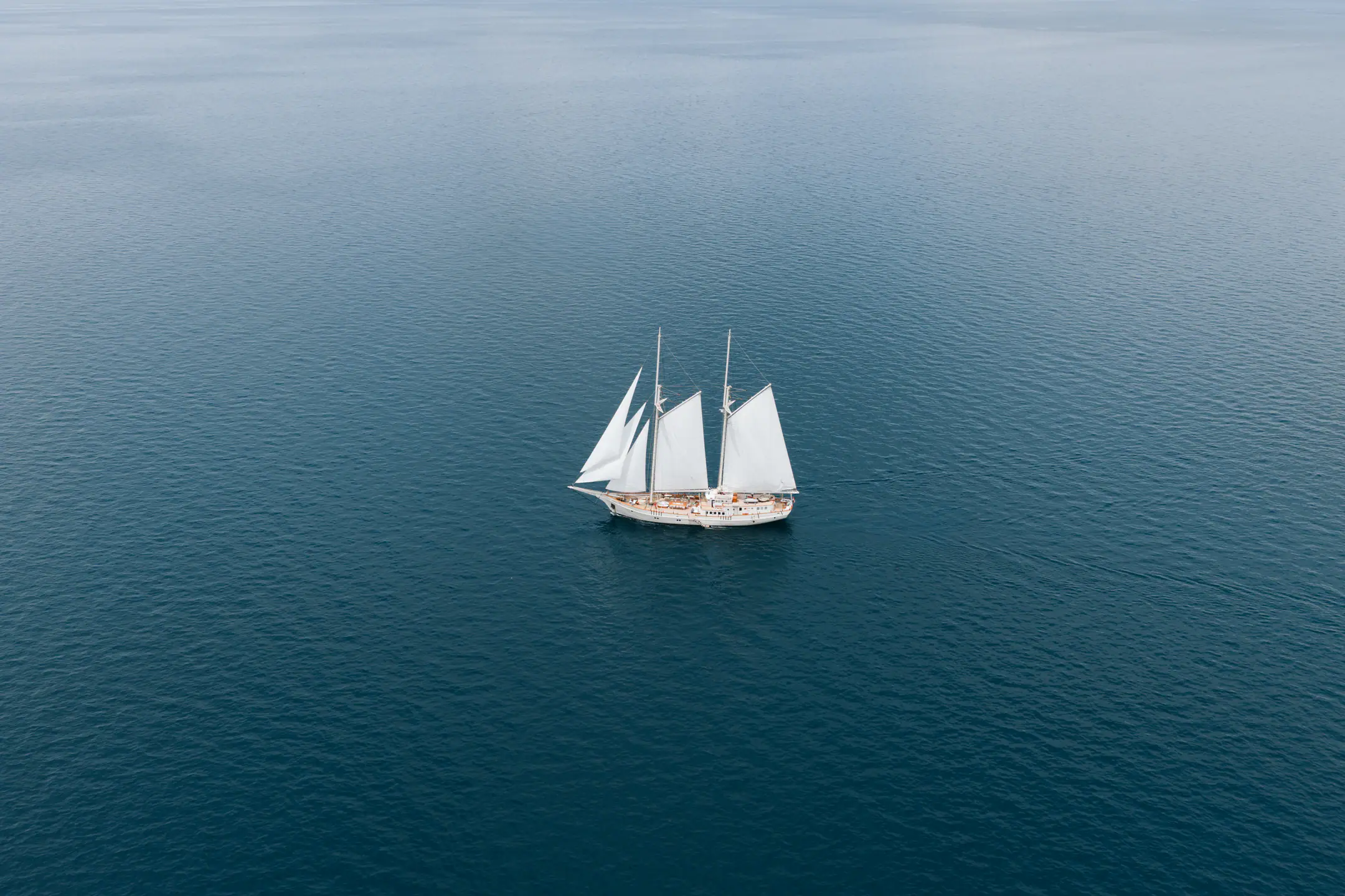 Mutiara Laut traditional sailing yacht drifting across calm turquoise waters.