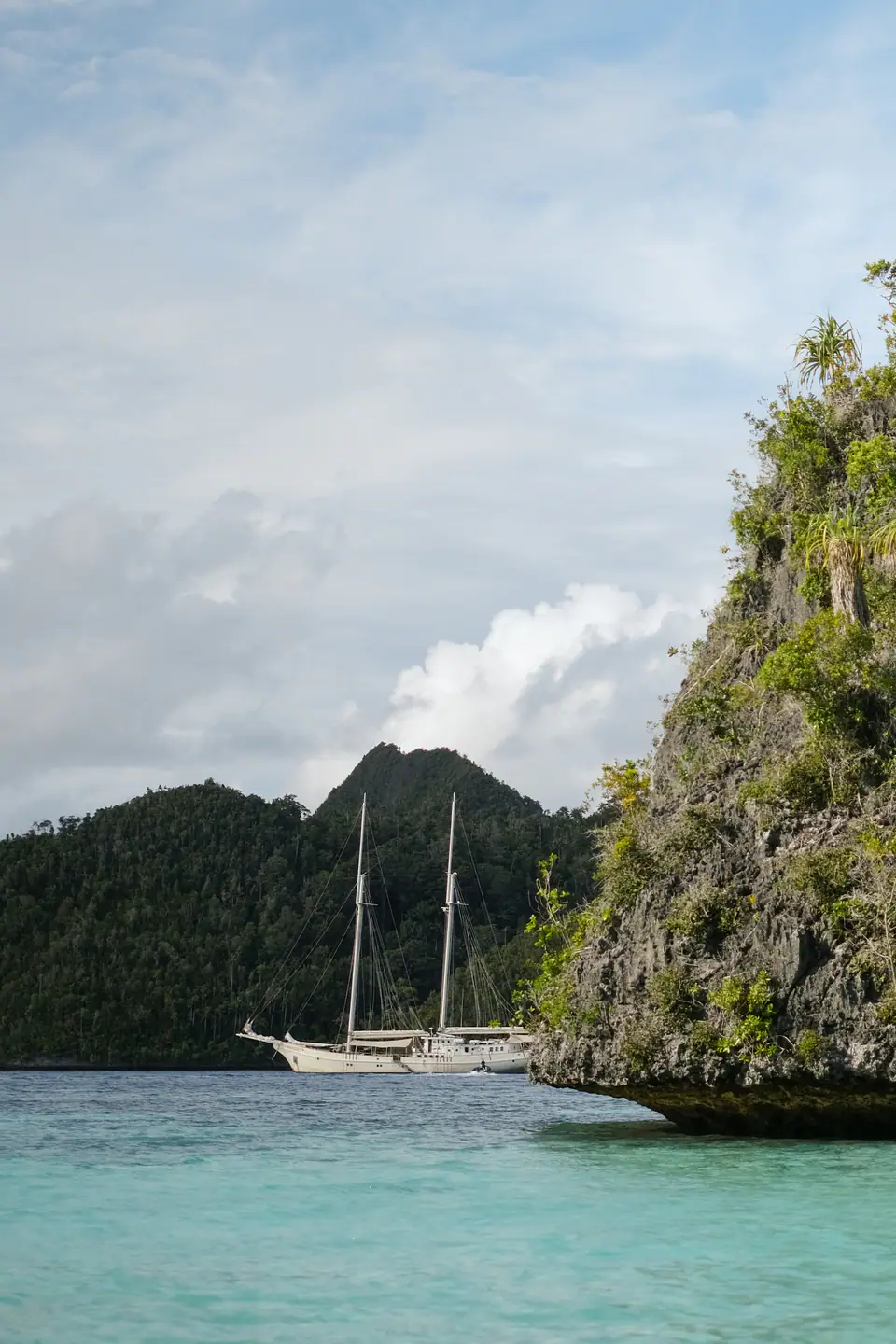 Mutiara Laut anchored beside dramatic limestone cliffs and turquoise waters.