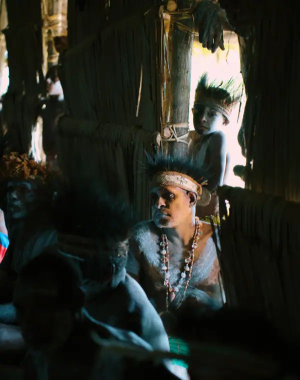 An Asmat elder is sitting in the corner and looking away.